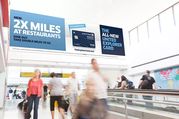 Airport travelers pass under prominent signage for the new United Explorer Card