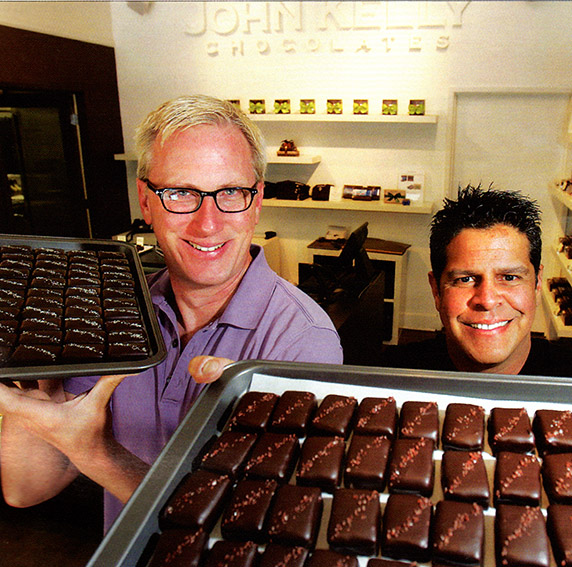 Two people holding trays with chocolate brownies