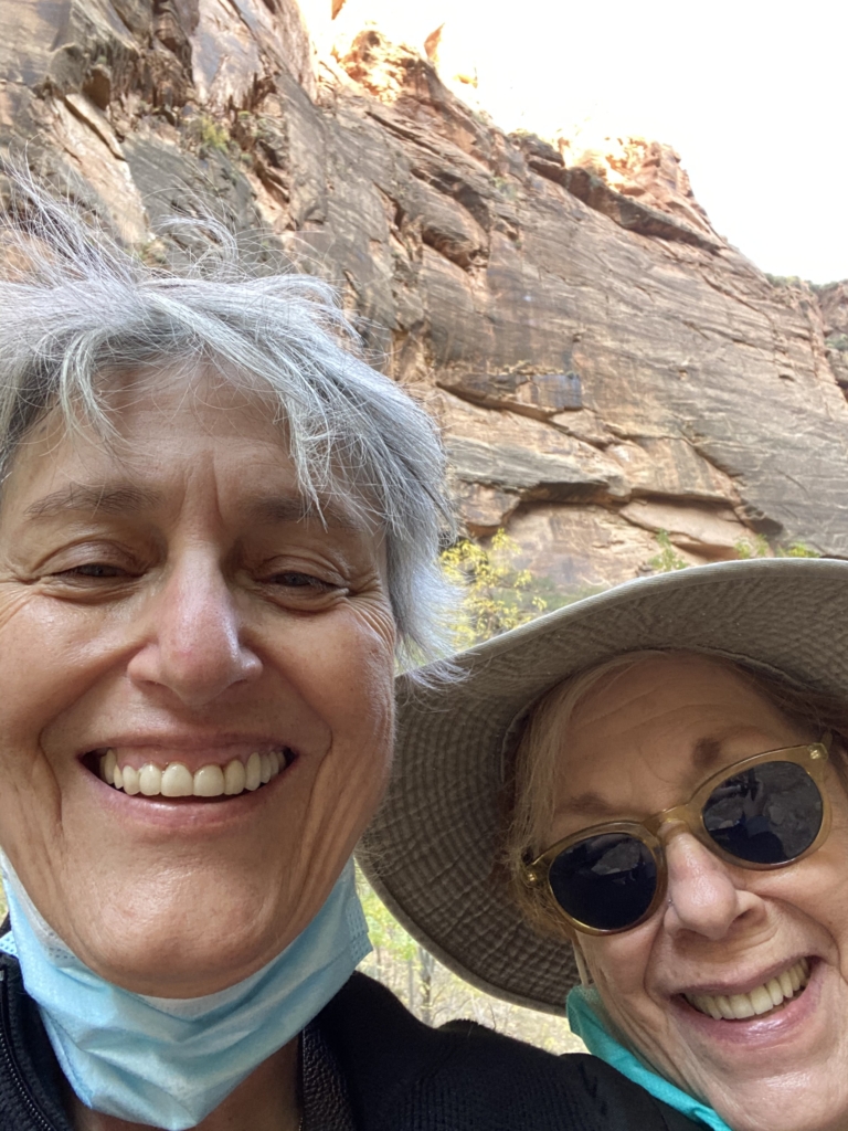 Two friends in the foreground smiling after a hike in Springdale, Utah.